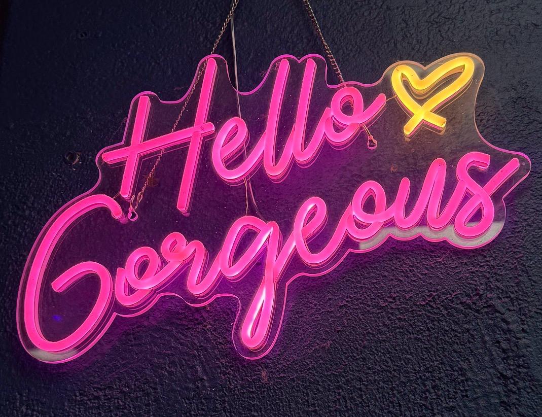 Neon 'Hello Gorgeous' sign on the wall at The Tanning Co.
